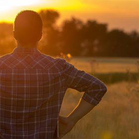 Cattle rancher looking out at pasture at sunset
